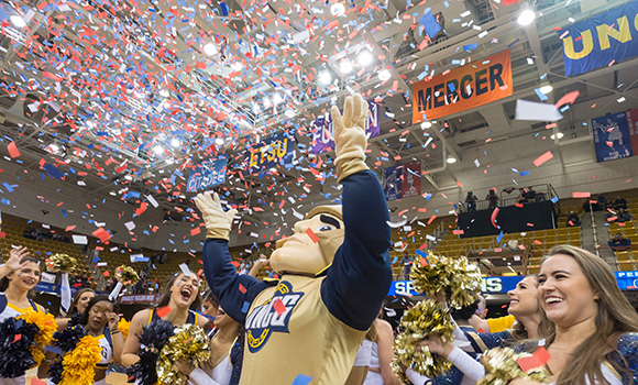 Photo of Spiro mascot and cheerleaders celebrating win with confetti on court