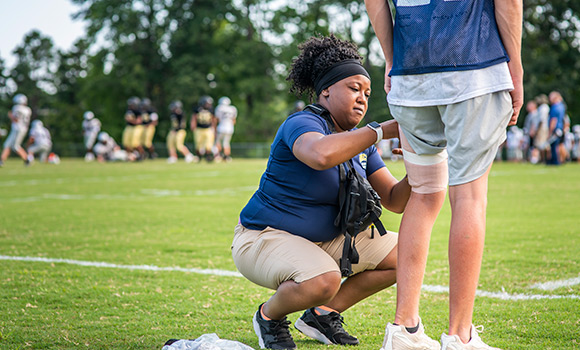 Photo of UNCG student applying bandage to athlete's leg