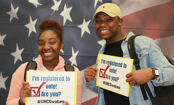Photo of students holding up "I'm registered to vote!" signs