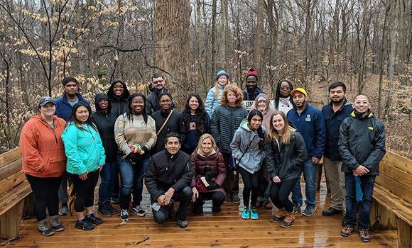 Group photo of students and faculty in front of tree.