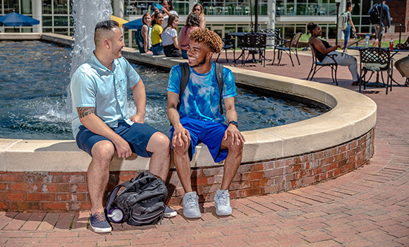 Photo of students talking at fountain on campus