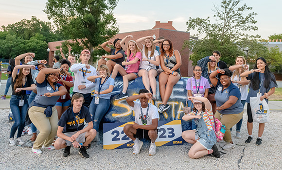 Group photo of SOAR students in front of rock on campus