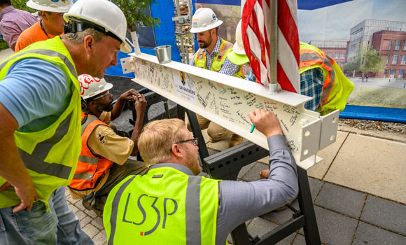 men in hard hats signing a steel beam