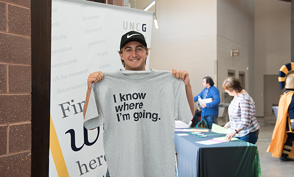 Photo of student holding up T-shirt at event