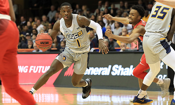 Photo of basketball player dribbling basketball past defenders