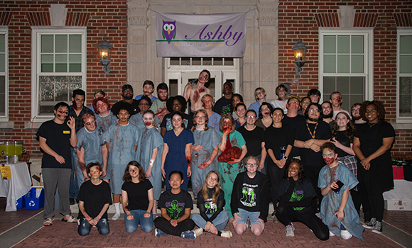 Students dressed as zombies and hospital personnel pose for a group photo in front of Foust Residence Hall