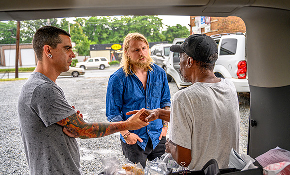 Photo of three men talking in parking lot