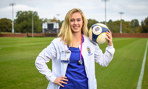Photo of Julia Brown in nursing scrubs on soccer field
