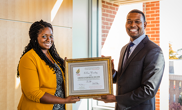 Ti'Era holding her certificate with Secretary of the N.C. Department of Environmental Quality Michael S. Regan