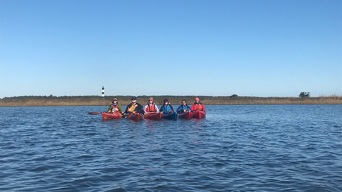 UNCG students kayaking on North Carolina shore.