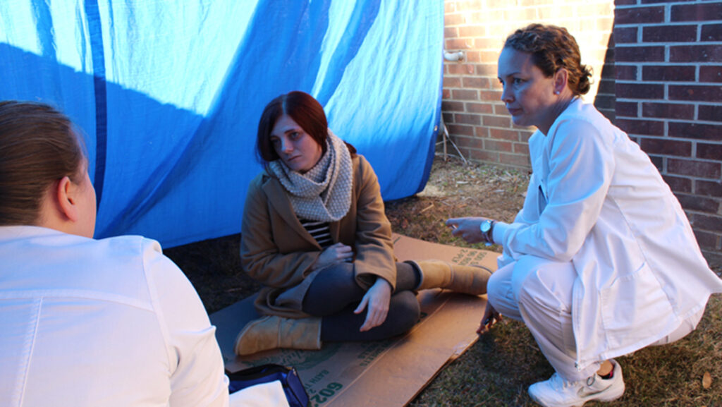 nursing students work with actors on ground