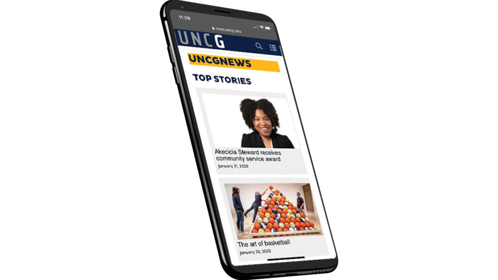 Photo of cell phone with image of UNCG News on screen