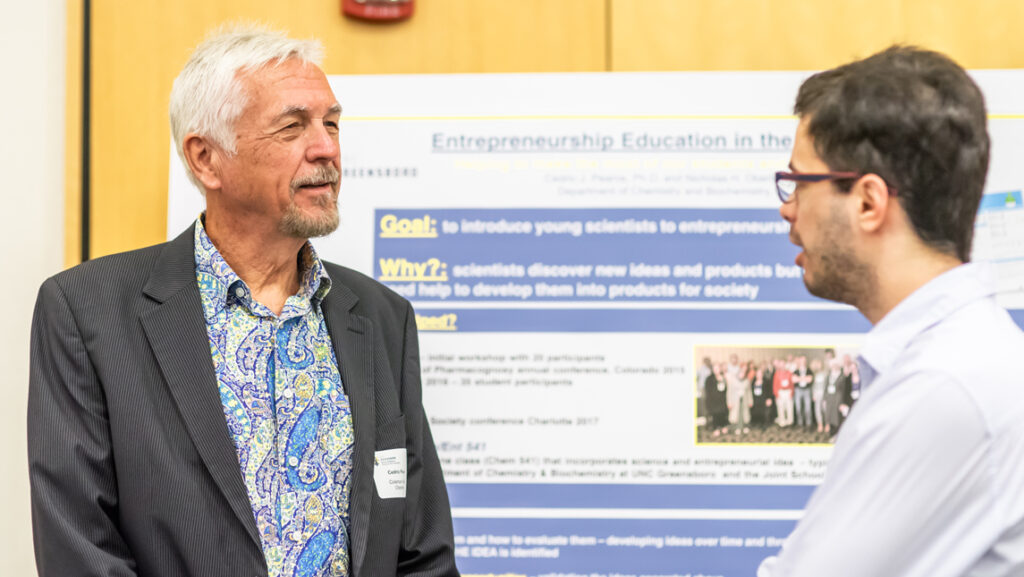 picture of researcher speaking to student in front of poster