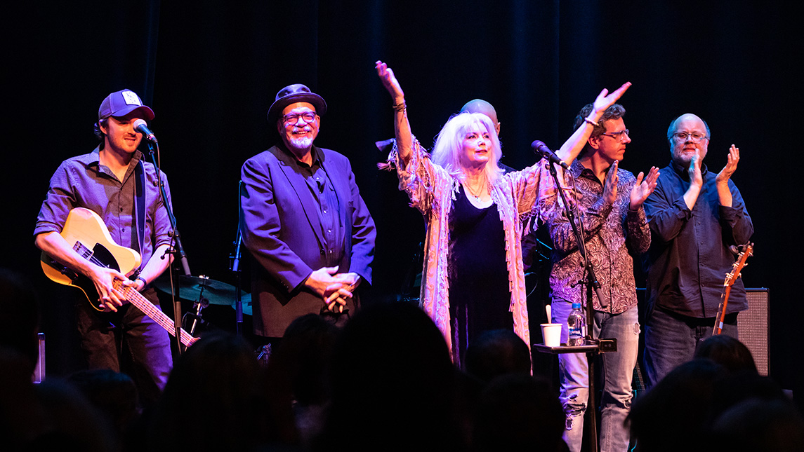 Emmylou Harris and band stand together at front of stage