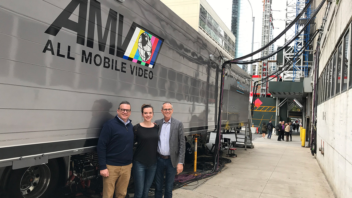 Photo of three people standing in front of large truck in city