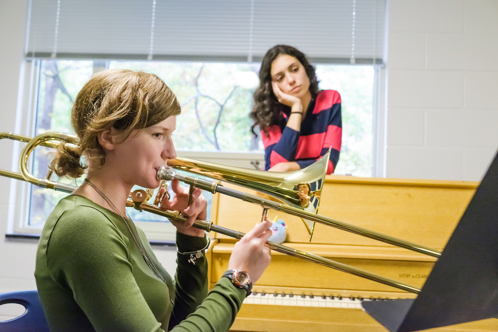 Photo of student playing trombone while other student watches