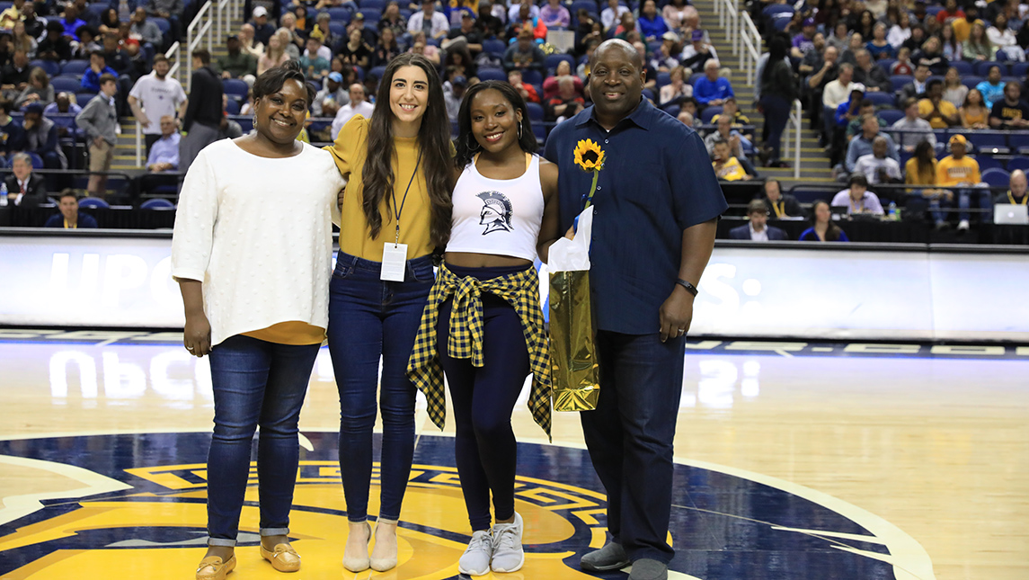 Photo of Amanda Stewart with family and coach at midcourt during game