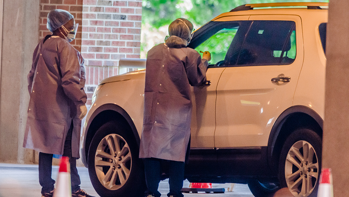 Photo of health care workers testing unidentified patient in car