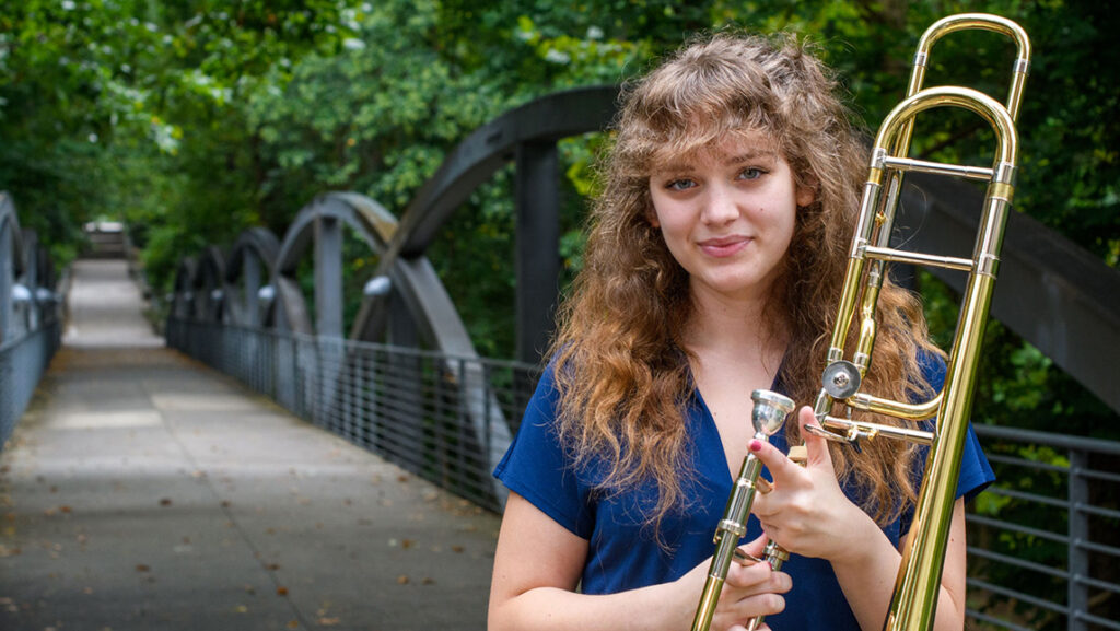 Photo of student holding trombone on campus