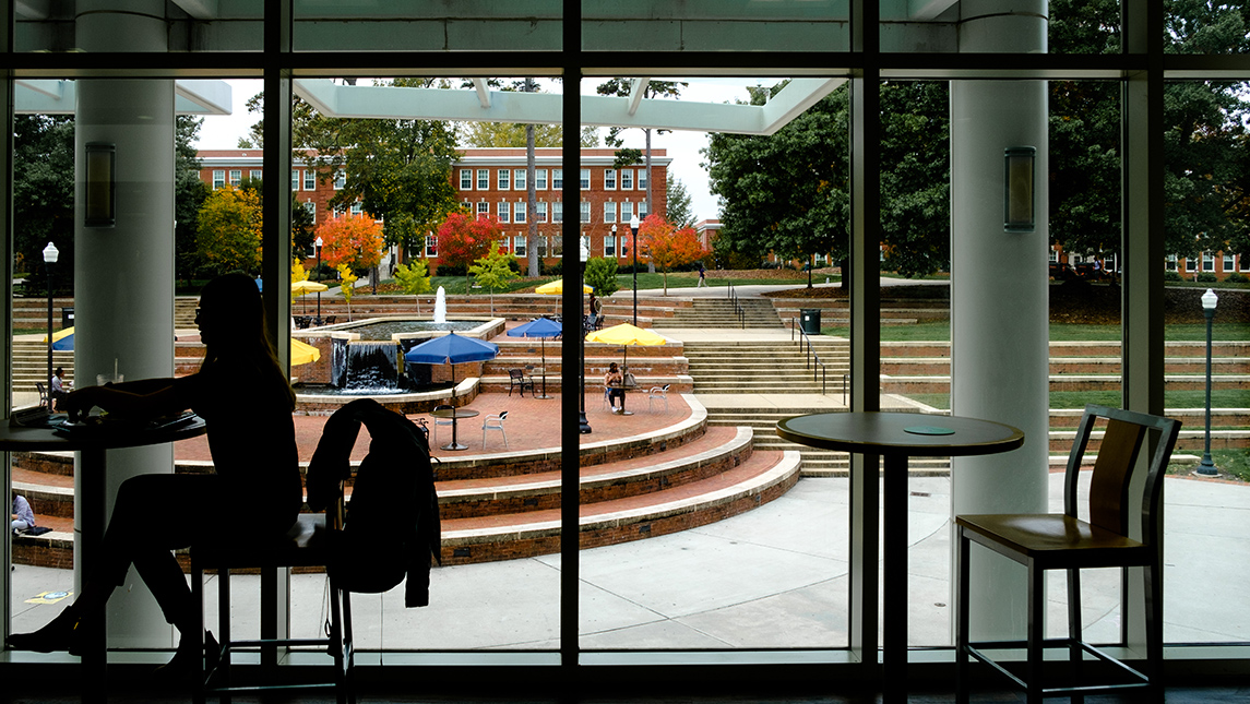 student in dining hall with fountain in background