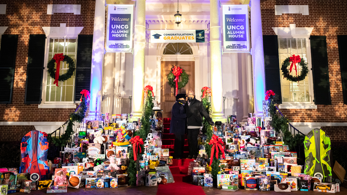 Chancellor Gilliam and Jacquie Gilliam in fron of Alumni House surrounded by donated toys