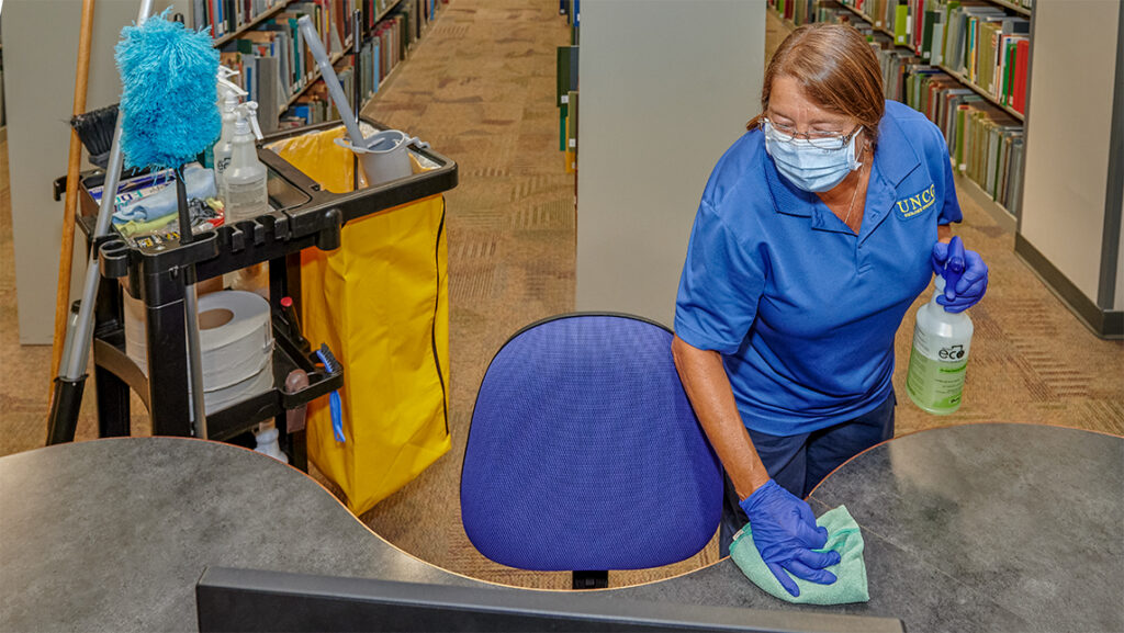 Housekeeper sanitizes a surface in the library