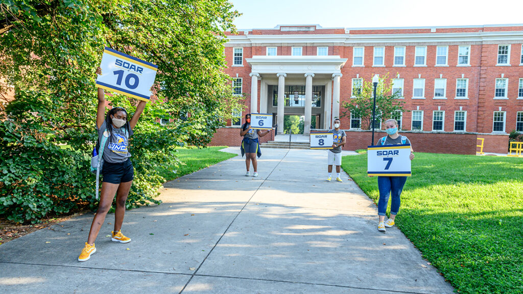 Student SOAR leaders standing six feet apart holding numbered signs