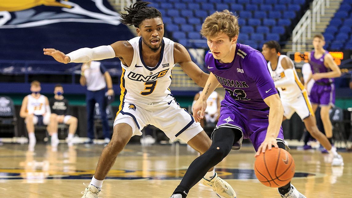 Action shot from basketball game in which UNCG player defends opponent