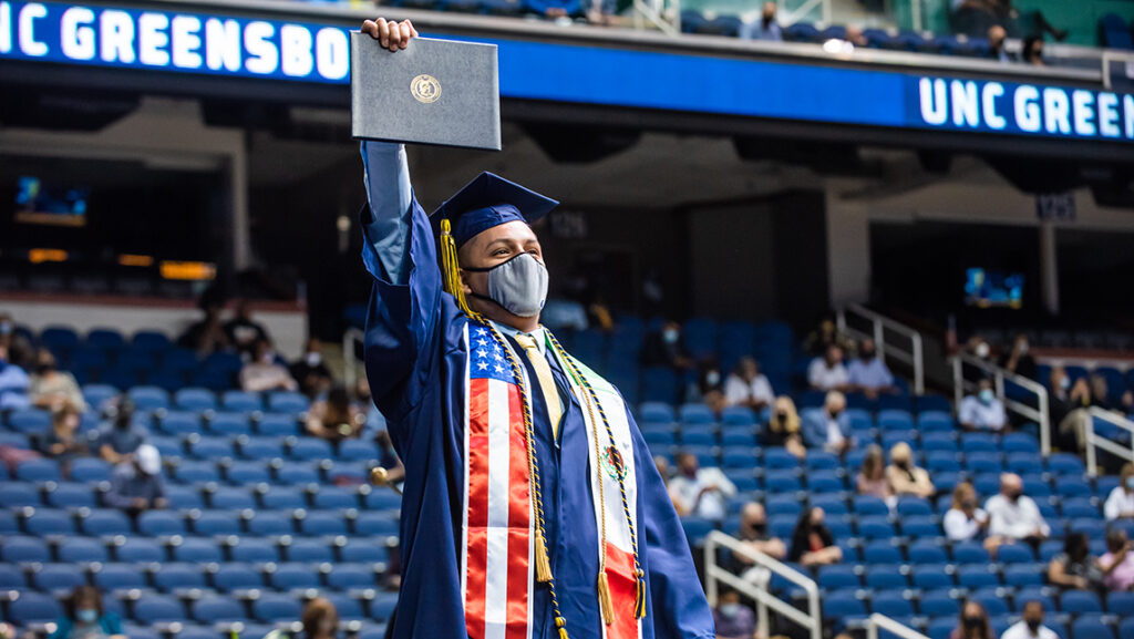 Student holding up diploma in celebration at commencement