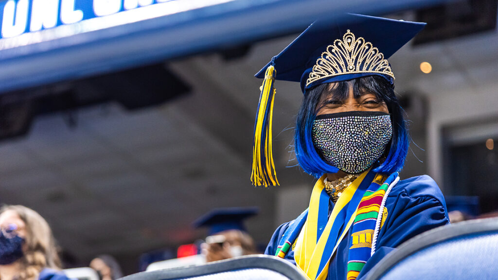 Student smiling (under mask) at commencement