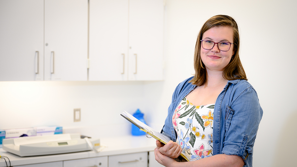 Portrait of student holding clipboard in clinical setting