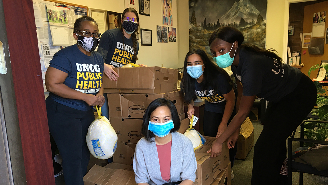 Dr. Morrison with four students standing around stacks of boxes of supplies