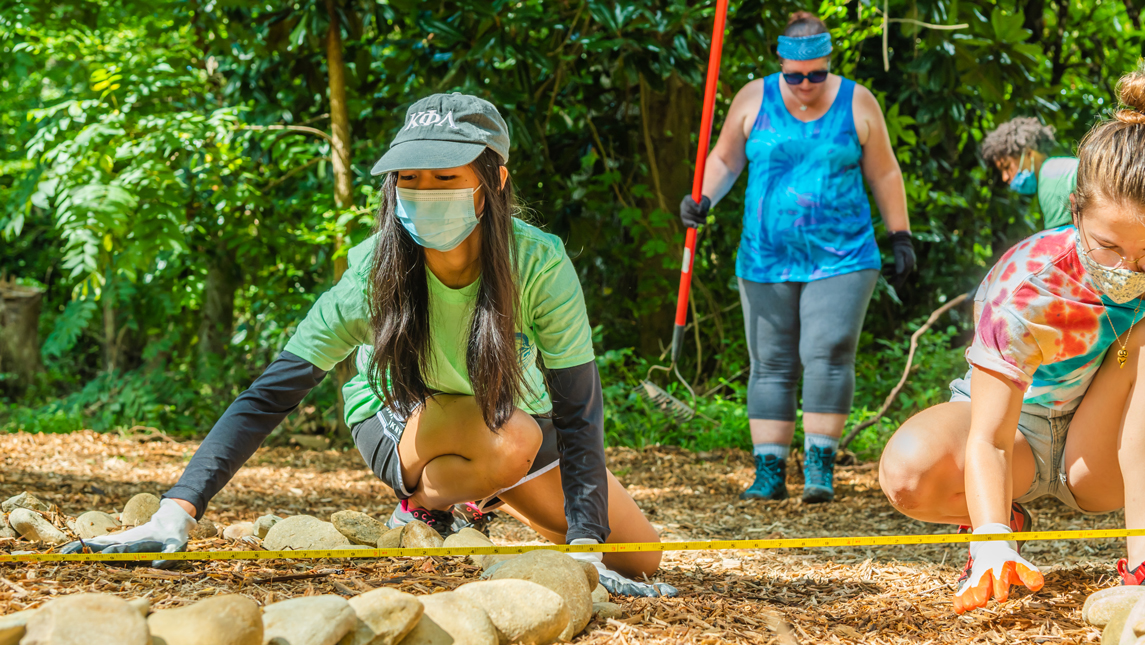 woman measuring distance on ground between rocks