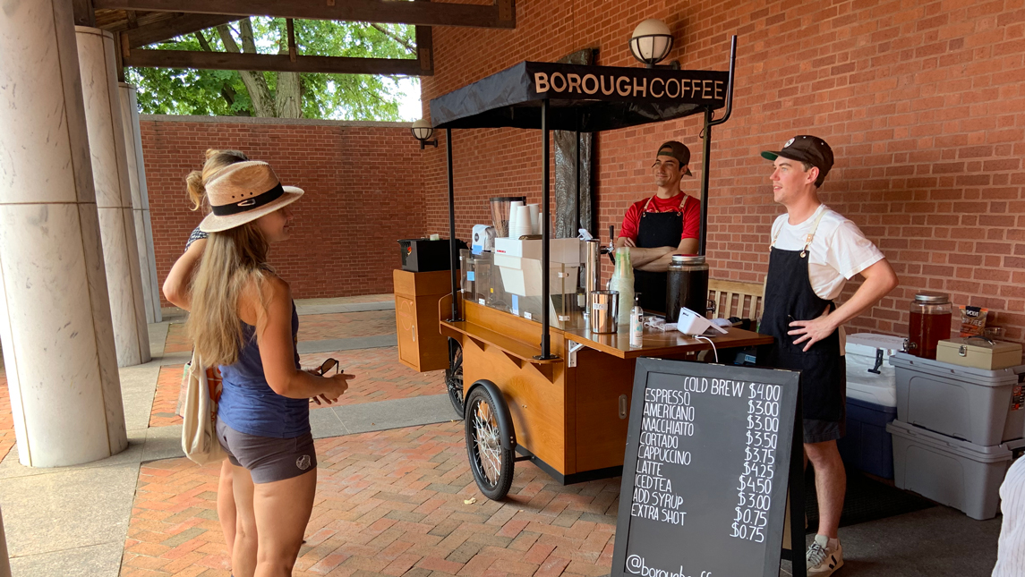 a coffee cart, with patrons and baristas