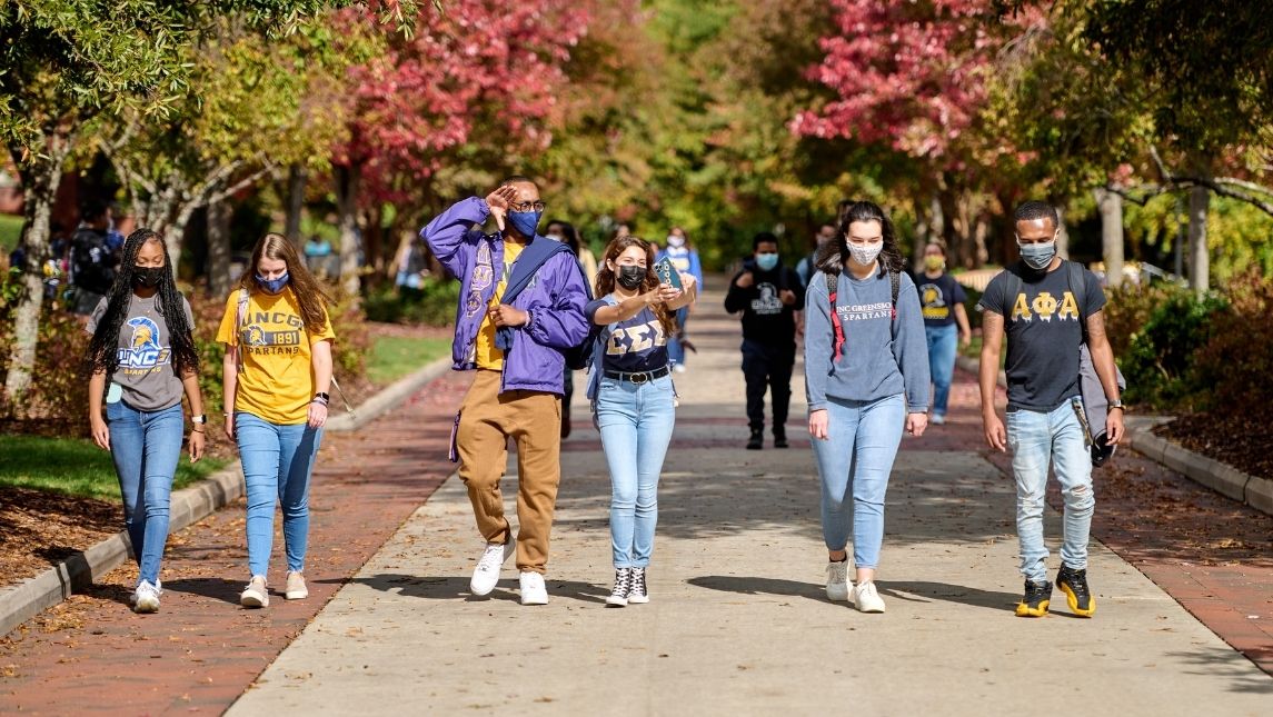 Group of six students walking down College Avenue in the fall