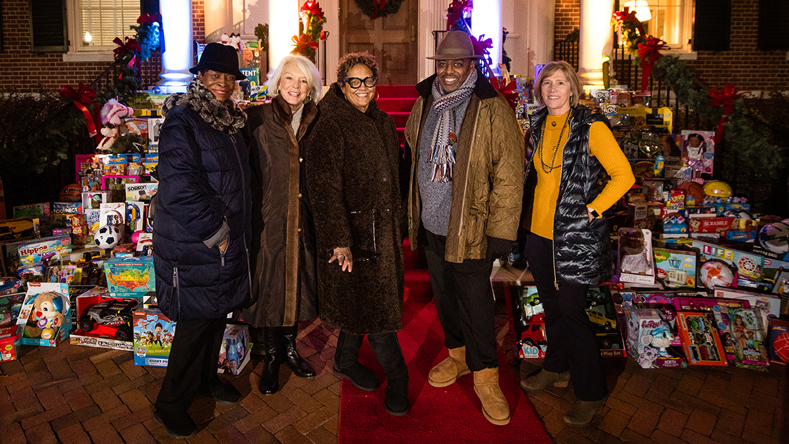 Trustee Mae Douglas, Board of Trustees Chair Betsy Oakley, Mrs. Jacquelean GIlliam, Chancellor Franklin D. Gilliam, Jr., and Trustee Margaret Benjamin stand in front of UNCG’s Alumni House with toys donated by the community during the fourth annual Toys for Joy event.