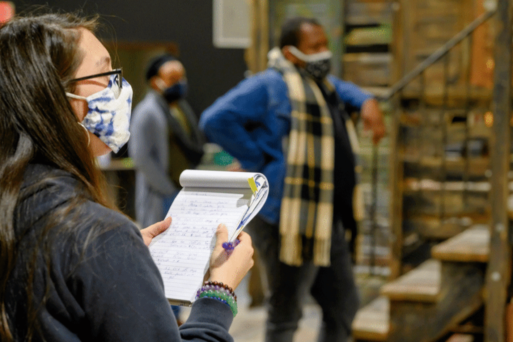 A woman reads notes on stage set