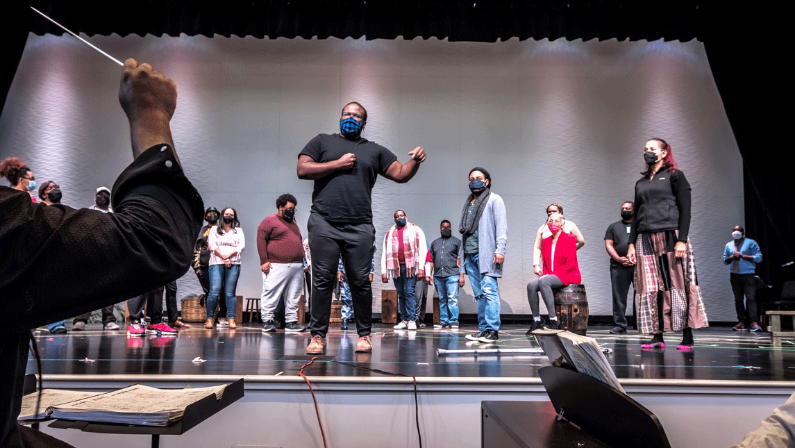 Several people on auditorium stage for opera rehearsal