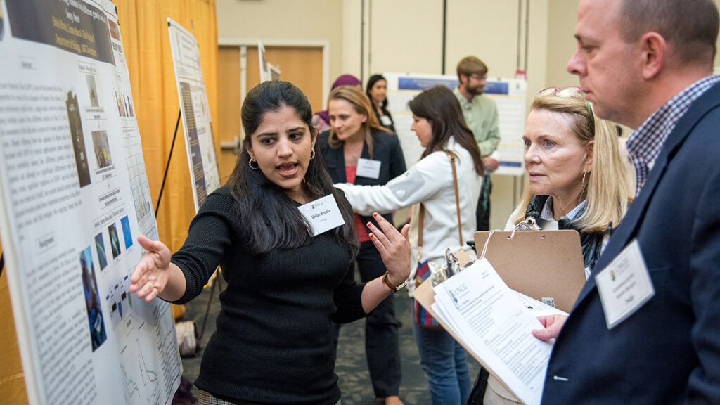A UNCG student points at a point on her posterboard.