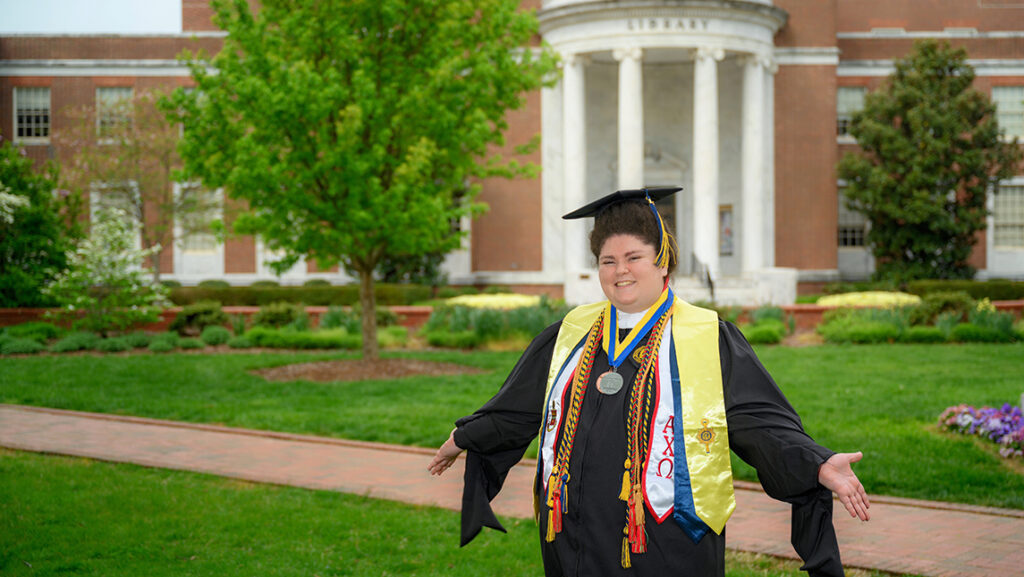 Christelle Barakat in full regalia standing in front of Jackson Library