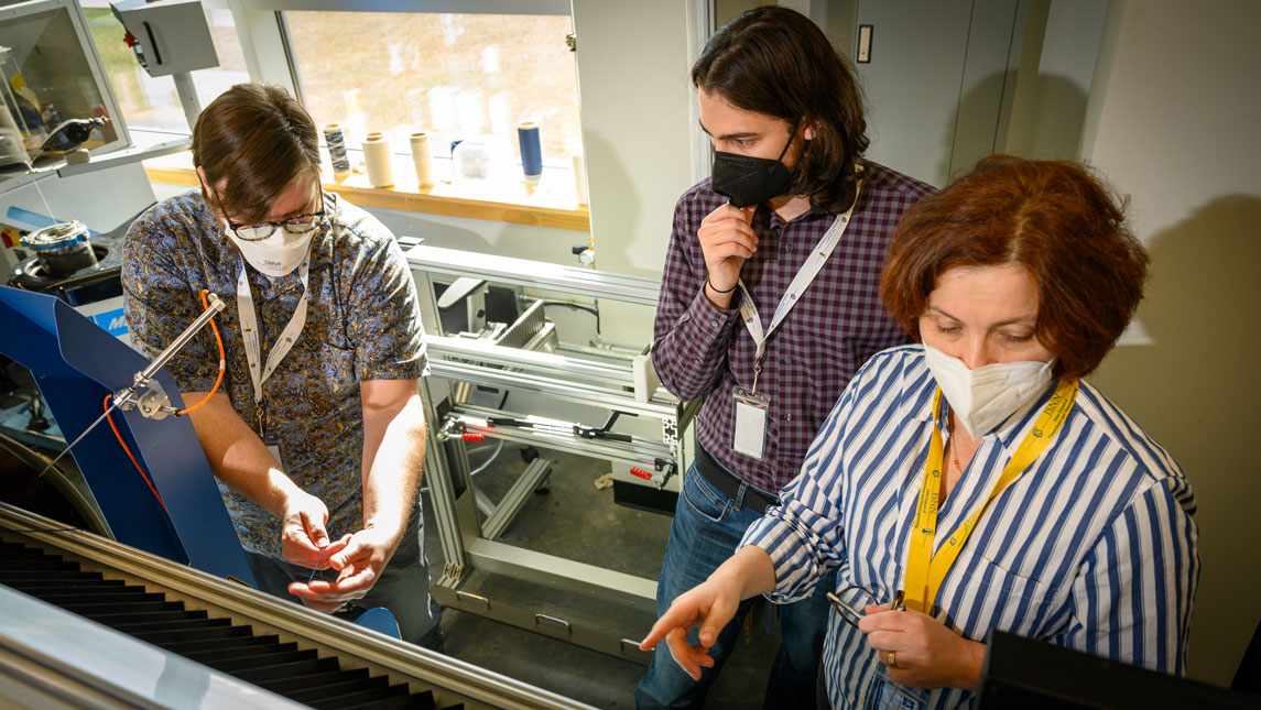 researchers with weaving machine