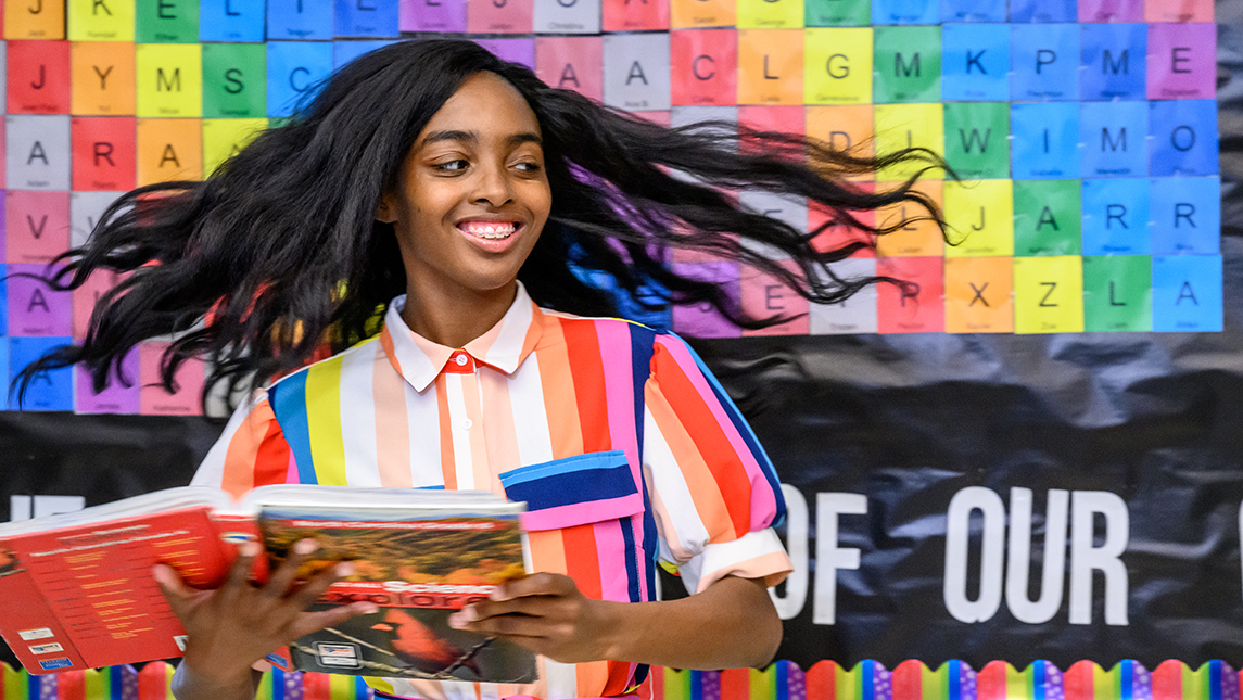 Yahira Robinson holding a book in a classroom