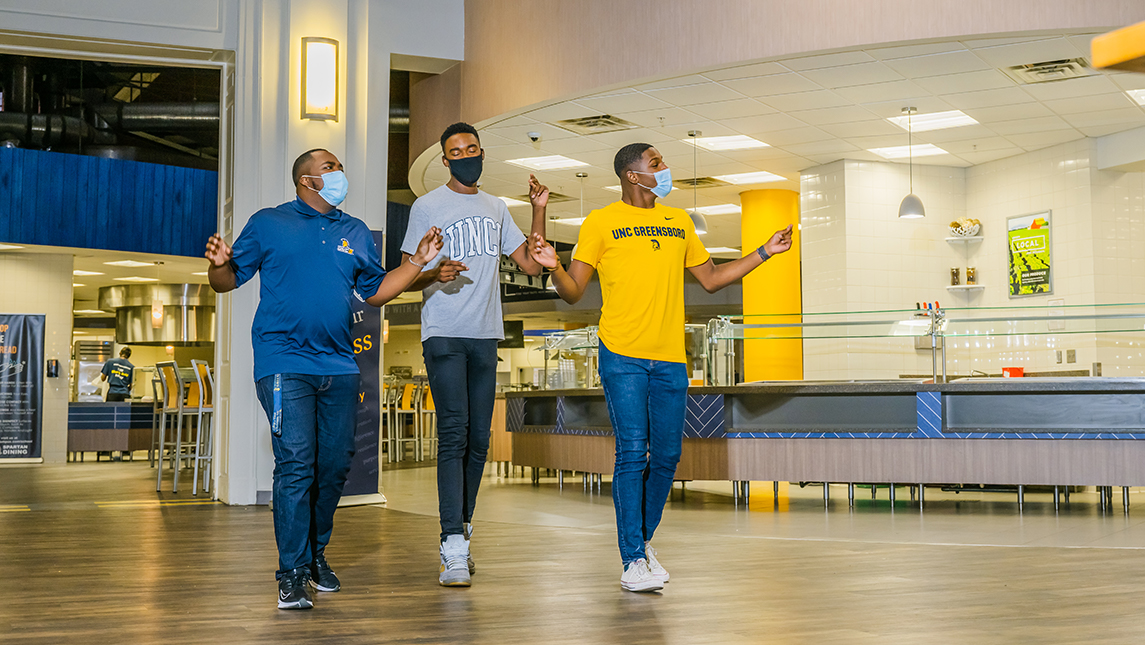 Julian Kennedy, Christoff Hairston, and Tavis Cunningham (1aChord) dance and sing in UNCG's Cafeteria