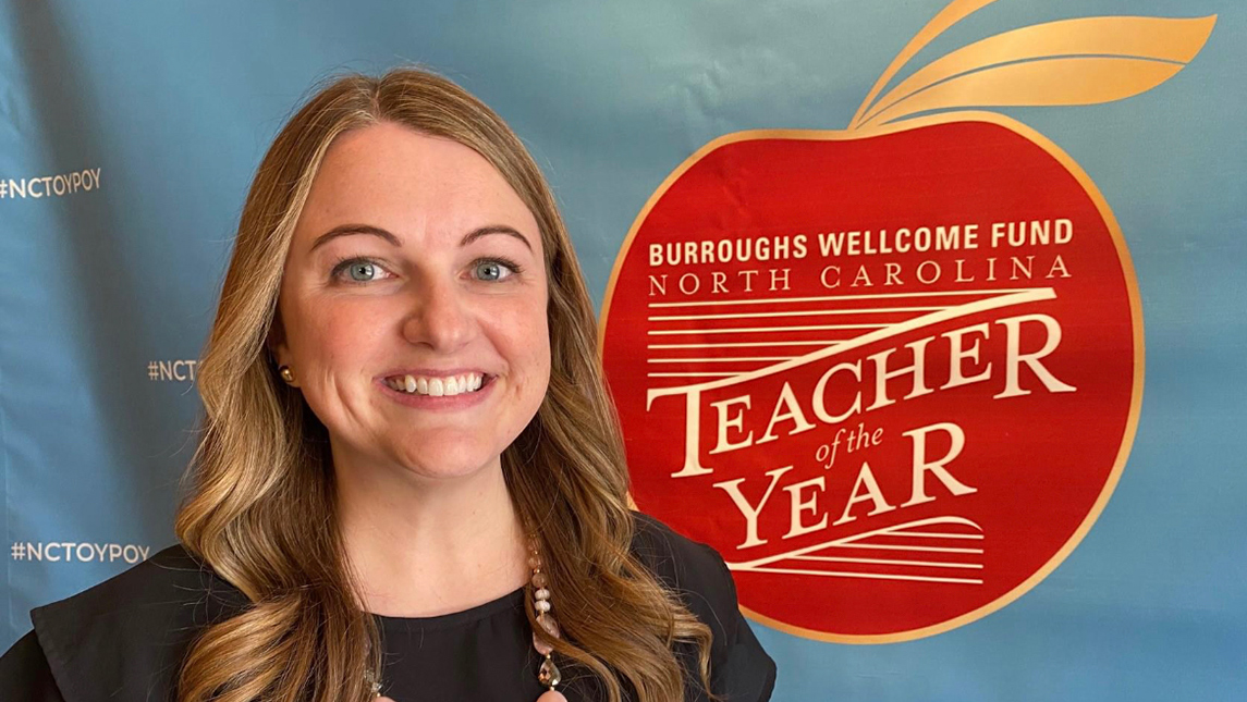 Leah Carper next to a poster reading "North Carolina Teacher of the Year"