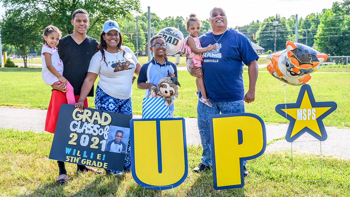 Moss Street Partnership School student celebrates with his family at 2021 moving up ceremony.