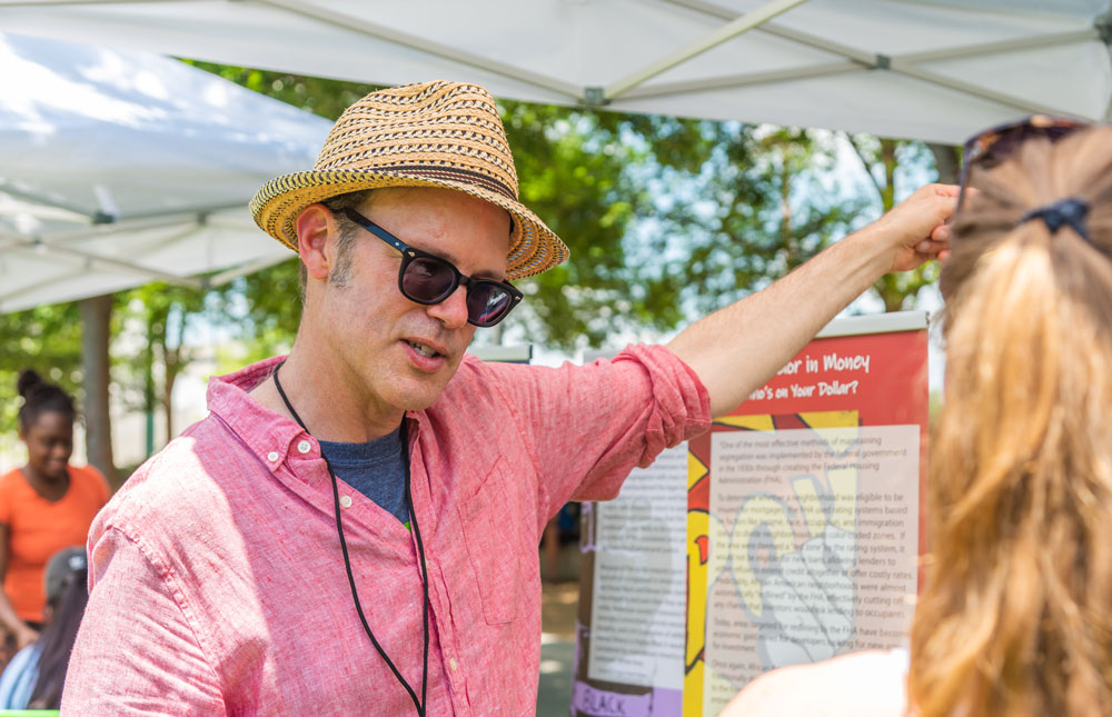 a man at a display table talking to a visitor