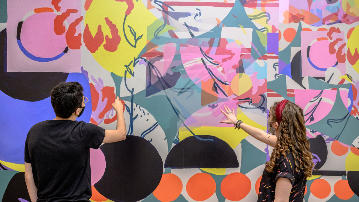 two art viewers in front of a colorful mural