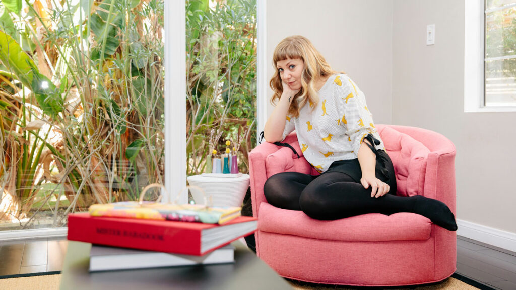 woman in her living room, books in the foreground