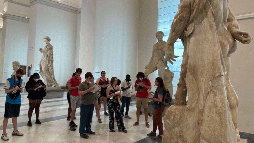 Students take notes in front of Roman statue for study abroad in Rome