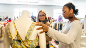 UNCG professor Anne Wood examines a dress designed by student on a mannequin